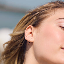 Photo de la moitié du visage d’une femme portant des boucles d’oreilles Gigi Supreme noires de Gigi Clozeau.