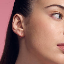 Photo du visage d’une femme portant des boucles d’oreilles classiques Gigi Clozeau de couleur rose fluo.
