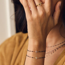 Poignet d’une femme portant différents bracelets de la nouvelle collection Spark en or noir Gigi Clozeau.