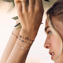 Photo du poignet d’une femme portant des bracelets de la collection Karma Gigi Clozeau de différentes couleurs.