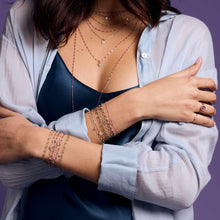 Photo des poignets d'une femme portant des bracelets Gigi Clozeau de différents modèles et couleurs.
