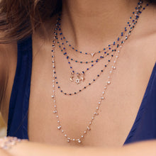 Photo du cou d’une femme portant des colliers Gigi Clozeau de couleur bleue.