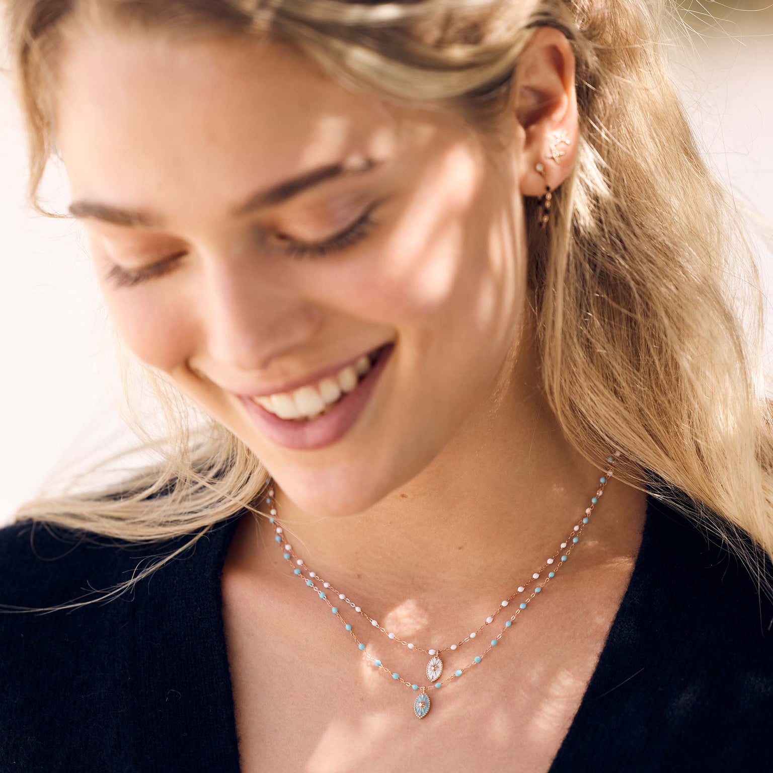 Photo du visage d’une femme portant autour du cou des pendentifs de la collection Karma Gigi Clozeau.