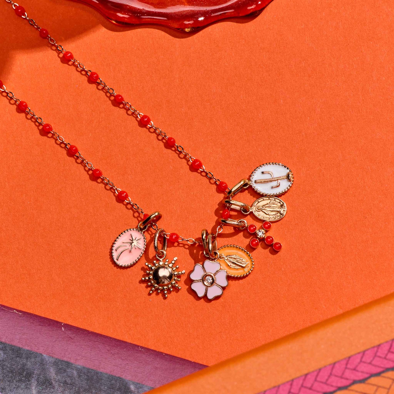 Photo de différent pendentifs Gigi Clozeau posé sur un fond orange 